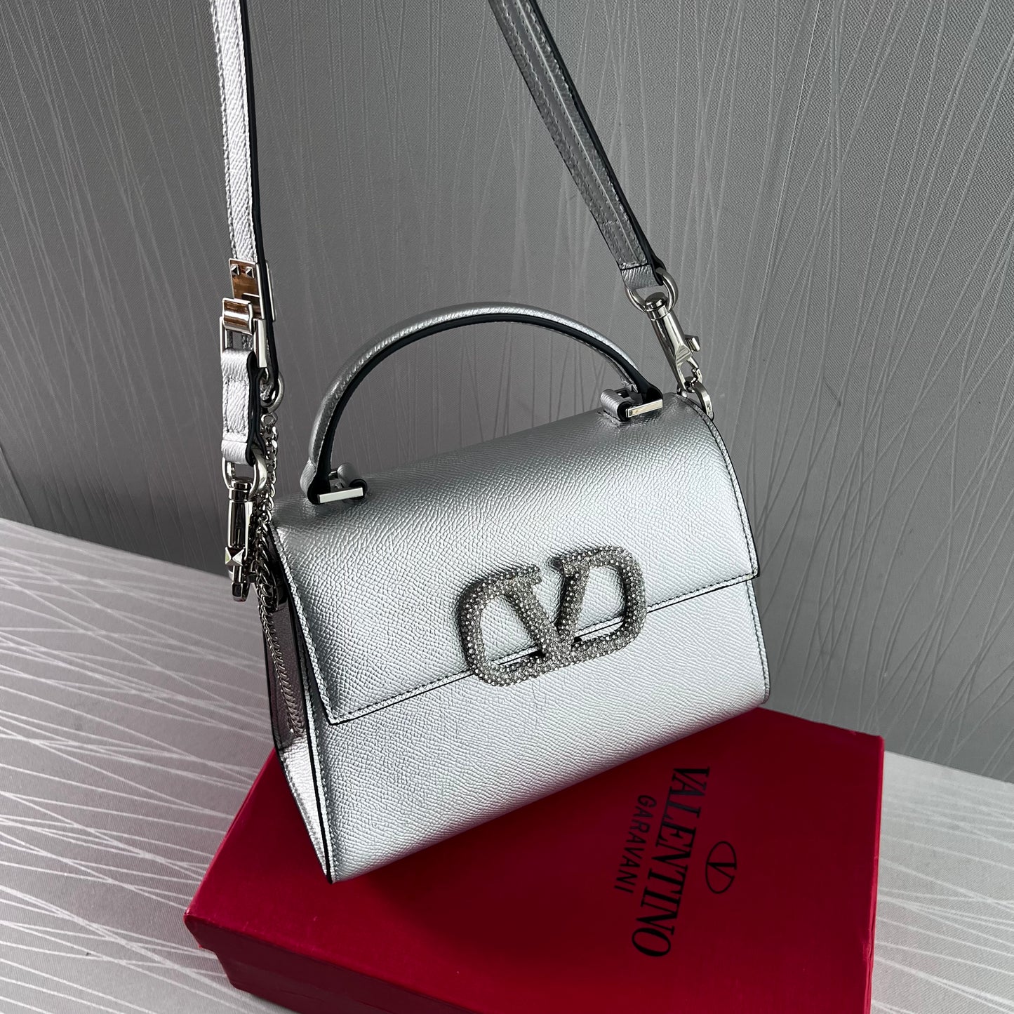 Bolso V piel color plata y herraje con piedras